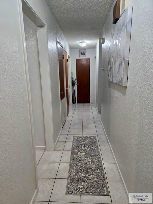 hallway with light tile patterned floors and a textured ceiling