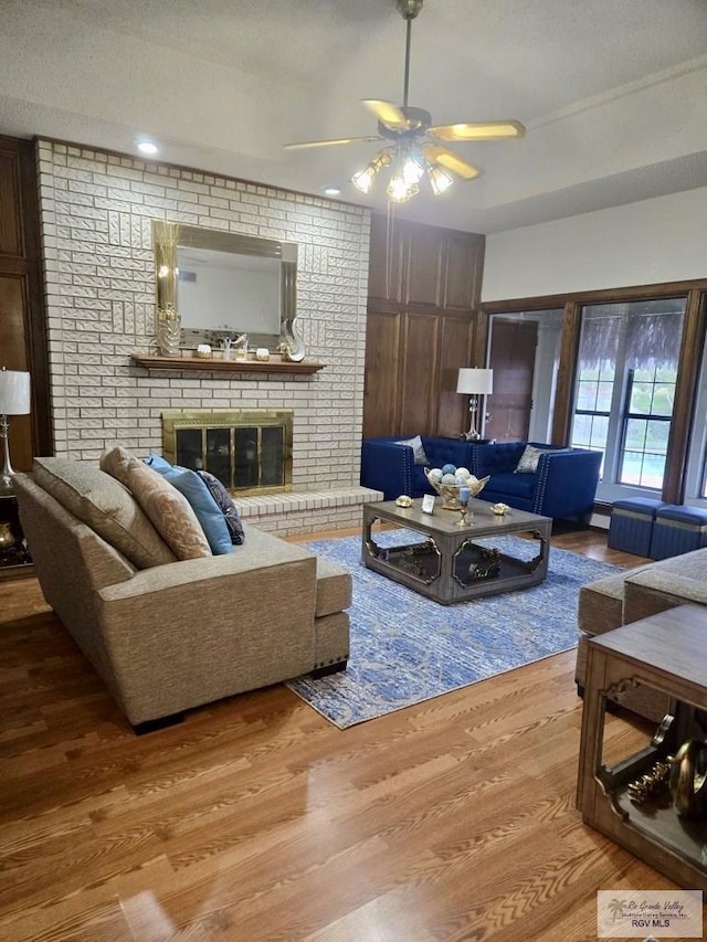 living room featuring a fireplace, hardwood / wood-style flooring, and ceiling fan