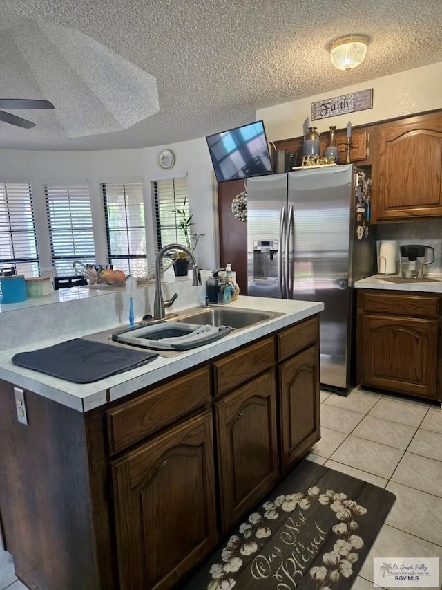 kitchen with light tile patterned flooring, a textured ceiling, ceiling fan, and sink