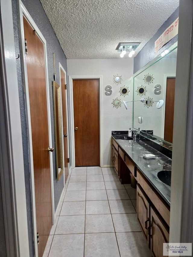 bathroom featuring tile patterned flooring, vanity, and a textured ceiling