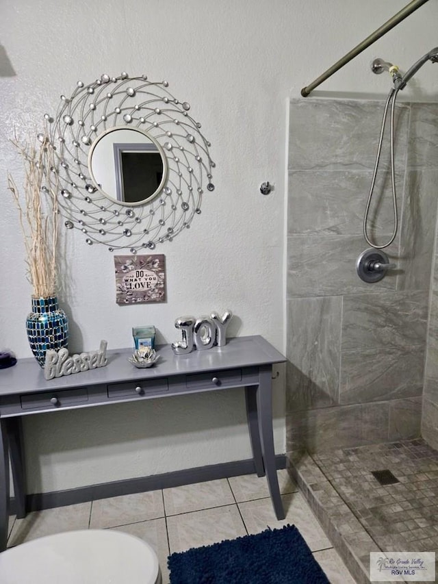 bathroom with toilet, a tile shower, and tile patterned floors