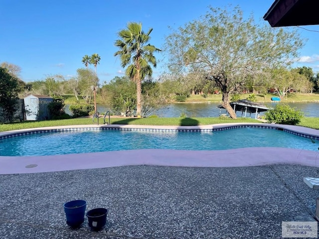 view of swimming pool featuring a shed, a yard, and a water view