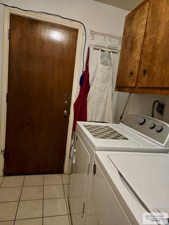 laundry area featuring cabinets, washing machine and dryer, light tile patterned floors, and a textured ceiling