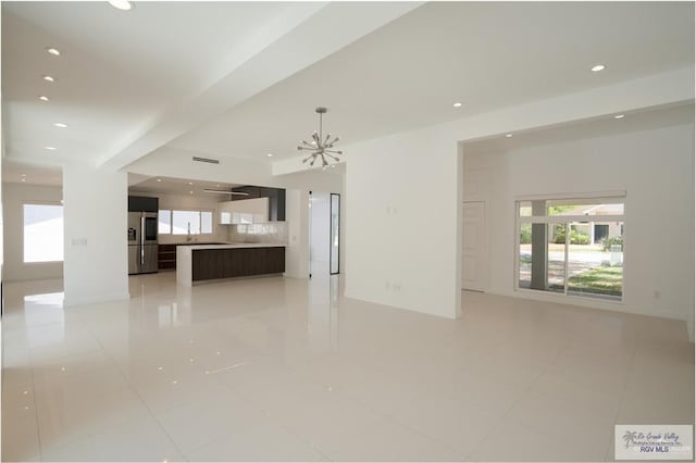 unfurnished living room featuring light tile patterned flooring, sink, and a chandelier