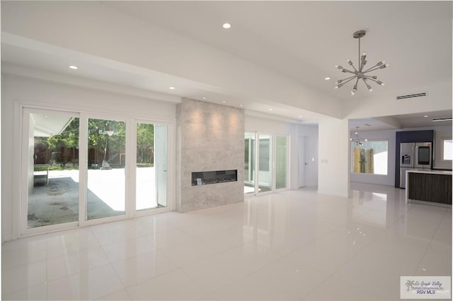 unfurnished living room with a fireplace, light tile patterned flooring, and a chandelier