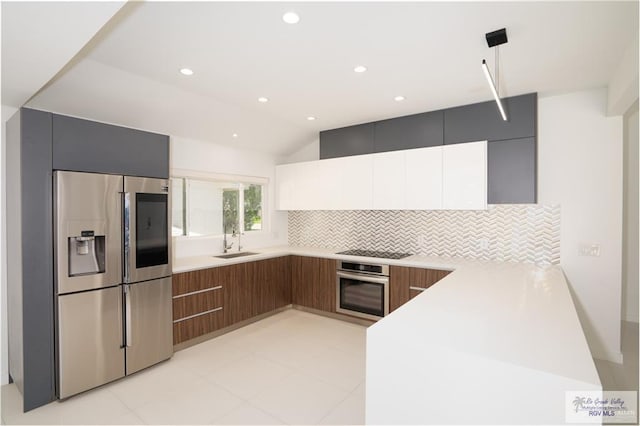 kitchen featuring lofted ceiling, sink, tasteful backsplash, white cabinetry, and stainless steel appliances