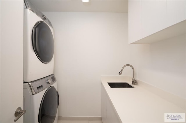 washroom with cabinets, tile patterned flooring, stacked washer / dryer, and sink