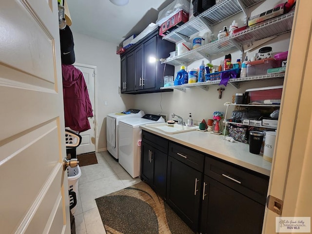 laundry area with cabinets, light tile patterned floors, separate washer and dryer, and sink