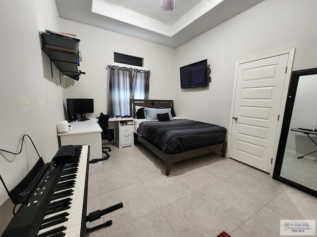 bedroom with light tile patterned flooring and a tray ceiling