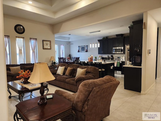 living room with a raised ceiling, plenty of natural light, and light tile patterned flooring