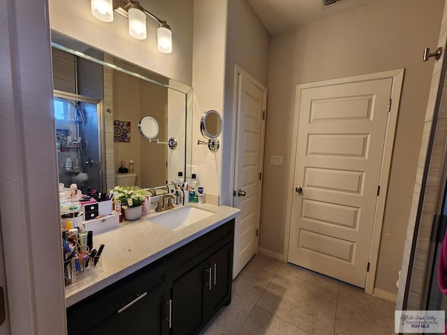 bathroom with tile patterned flooring, vanity, toilet, and a shower with door