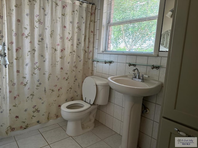 1406 E Bowie Ave, Harlingen, TX 78550 - bathroom with toilet, tile patterned floors, tile walls, and curtained shower