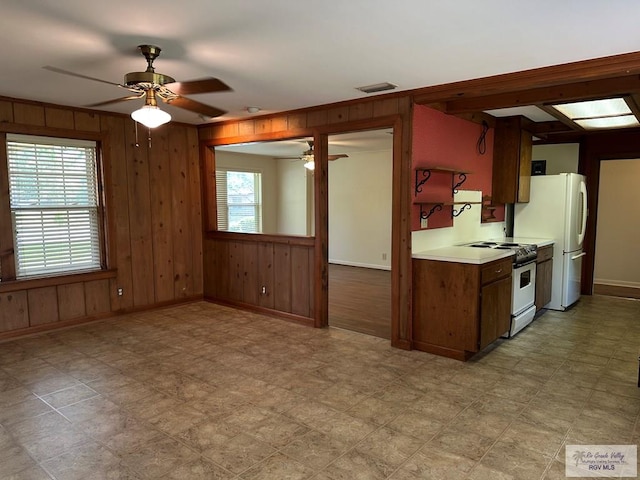 1406 E Bowie Ave, Harlingen, TX 78550 - kitchen featuring white appliances, a ceiling fan, baseboards, wood walls, and light countertops