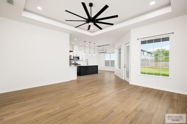 3515 S Elevation Dr, Edinburg, TX 78542 - unfurnished living room with a tray ceiling, light wood-style floors, ceiling fan, recessed lighting, and baseboards
