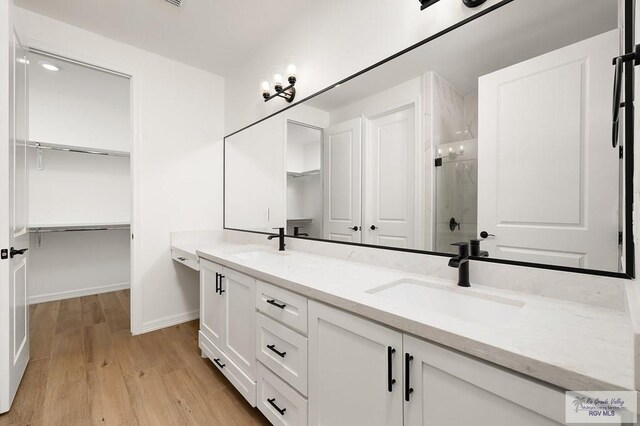 3515 S Elevation Dr, Edinburg, TX 78542 - bathroom with a stall shower, double vanity, wood finished floors, baseboards, and a spacious closet