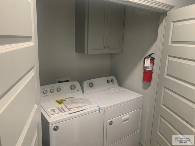 clothes washing area with washer and clothes dryer and cabinets