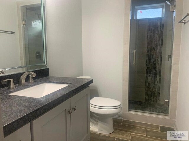 bathroom with an enclosed shower, vanity, and toilet