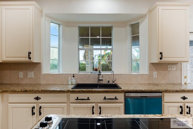 kitchen featuring stainless steel dishwasher, sink, light stone countertops, and backsplash