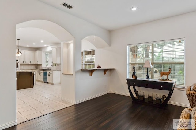 kitchen with light wood-type flooring, stainless steel appliances, sink, pendant lighting, and white cabinetry