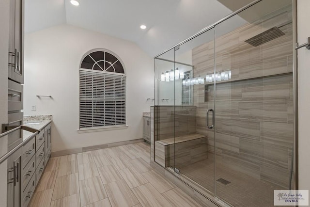 bathroom featuring vanity, a shower with shower door, and vaulted ceiling