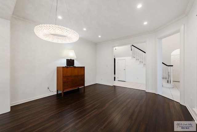 unfurnished living room featuring hardwood / wood-style flooring, crown molding, and a notable chandelier