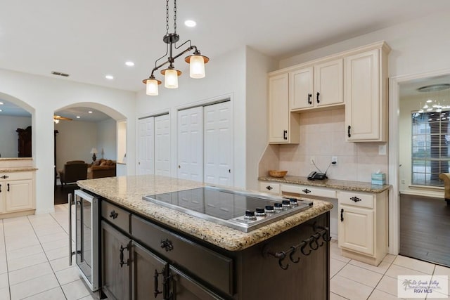 kitchen with dark brown cabinets, stainless steel gas cooktop, beverage cooler, a center island, and hanging light fixtures