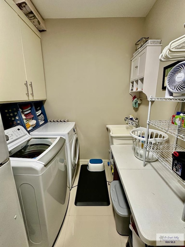 clothes washing area featuring light tile patterned floors, cabinet space, baseboards, and separate washer and dryer