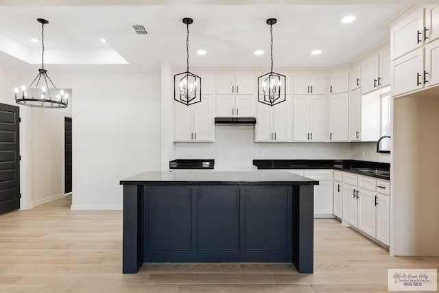 1209 Bridle Way, San Benito, TX 78586 - kitchen featuring a chandelier, dark countertops, under cabinet range hood, light wood-style floors, and recessed lighting