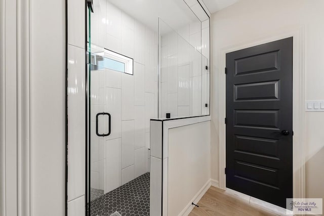 bathroom with hardwood / wood-style floors and a shower with shower door