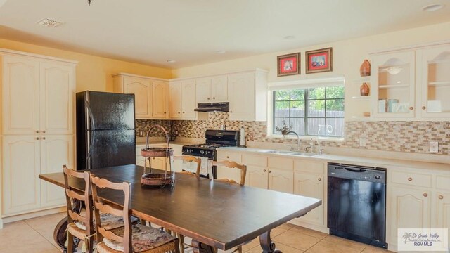 kitchen with backsplash, sink, light tile patterned floors, and black appliances