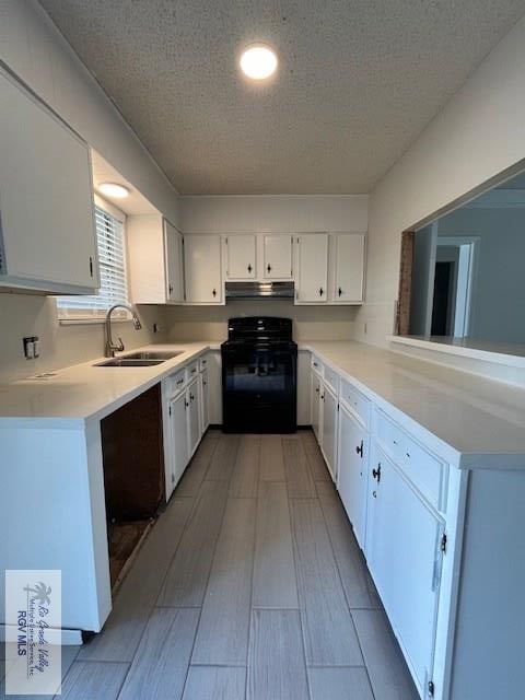 kitchen featuring black stove, sink, light hardwood / wood-style flooring, a textured ceiling, and white cabinetry