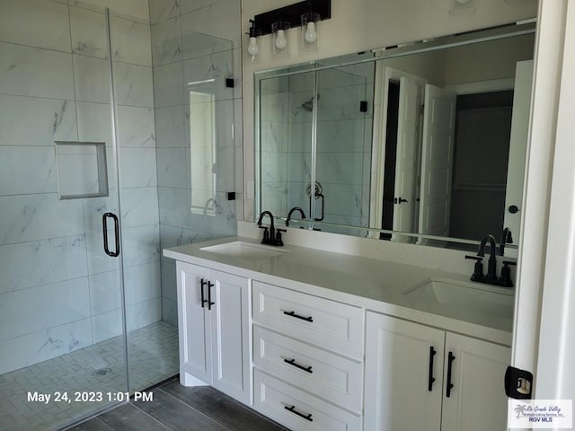full bathroom with double vanity, a shower stall, and a sink