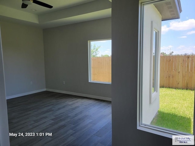 unfurnished room with baseboards, ceiling fan, and dark wood-style floors