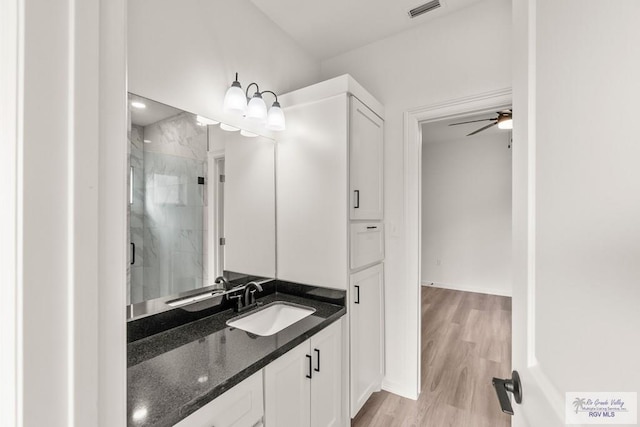 full bathroom featuring ceiling fan, visible vents, a shower stall, wood finished floors, and vanity
