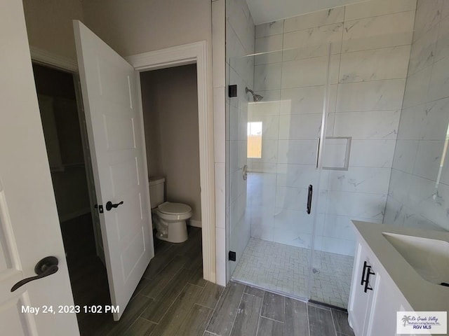 bathroom featuring vanity, wood tiled floor, toilet, and a shower stall