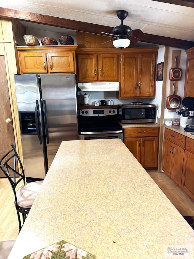 kitchen with a kitchen bar, ceiling fan, light hardwood / wood-style flooring, and stainless steel appliances