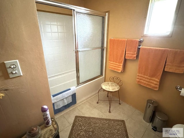 bathroom with tile patterned flooring and bath / shower combo with glass door