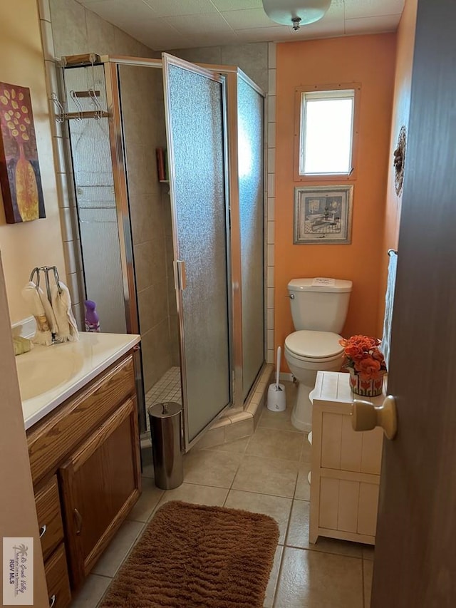 bathroom with tile patterned floors, toilet, vanity, and walk in shower