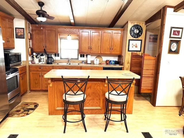 kitchen featuring a breakfast bar area, a center island, light wood-type flooring, and appliances with stainless steel finishes