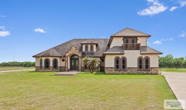 450 Bobcat St, San Benito, TX 78586 - view of front of house featuring french doors, stucco siding, a balcony, and a front lawn