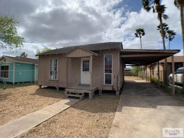 manufactured / mobile home with a carport, roof with shingles, concrete driveway, and fence