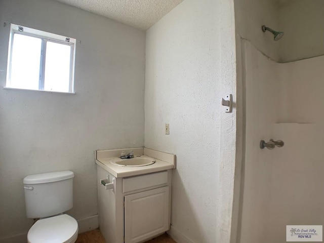 bathroom featuring a shower, toilet, vanity, and a textured ceiling