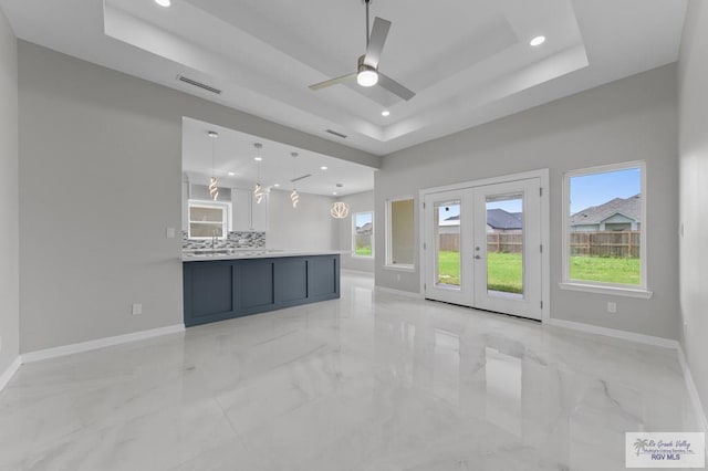 32722 Jorge St, Los Fresnos, TX 78566 - unfurnished living room with a raised ceiling, french doors, light marble finish flooring, and recessed lighting