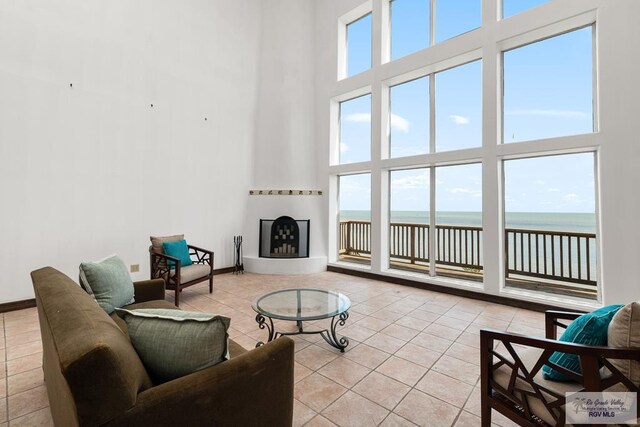 1810 N Shore Dr, Port Isabel, TX 78578 - living room featuring a high ceiling, light tile patterned floors, a water view, and a glass covered fireplace