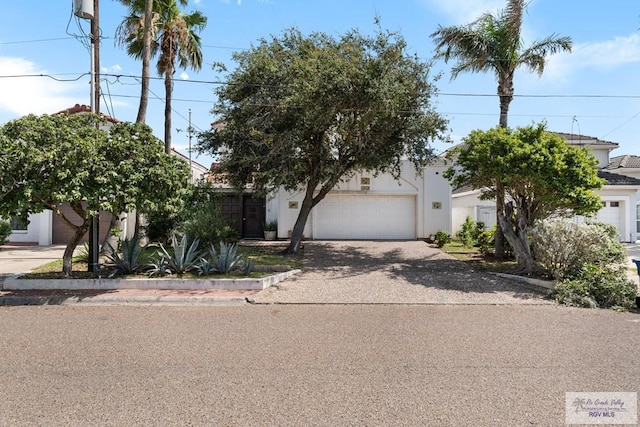 1810 N Shore Dr, Port Isabel, TX 78578 - obstructed view of property featuring driveway, an attached garage, and stucco siding