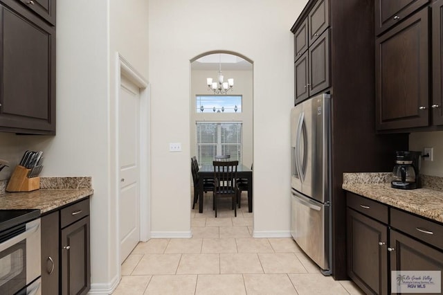 kitchen featuring light stone countertops, an inviting chandelier, appliances with stainless steel finishes, and light tile patterned flooring