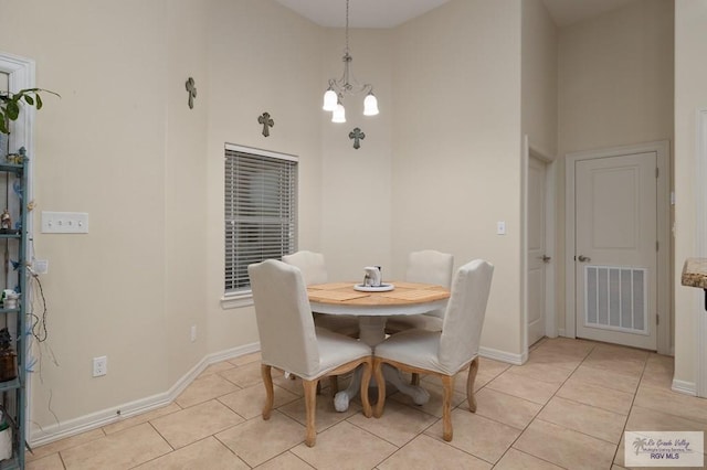 tiled dining area featuring a towering ceiling and a notable chandelier