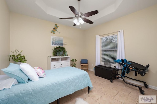 tiled bedroom featuring ceiling fan and a tray ceiling