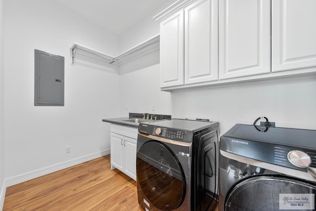 laundry area featuring light wood-type flooring, sink, electric panel, and separate washer and dryer