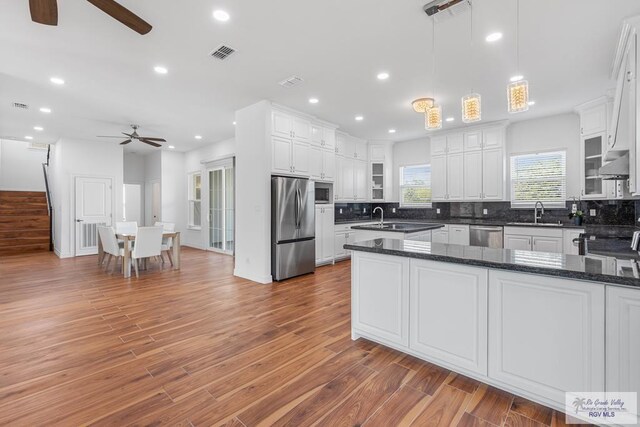 kitchen with dark hardwood / wood-style floors, white cabinetry, stainless steel appliances, and decorative light fixtures